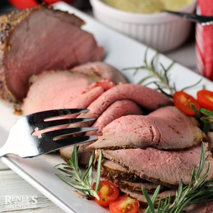 Eye of Round Roast on a white serving platter garnished with rosemary.