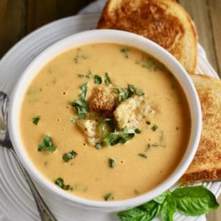 A bowl of tomato soup with a grilled cheese sandwich.