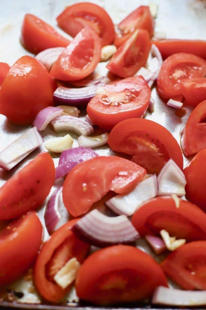 Cut up tomatoes, onion and garlic on a baking sheet. 