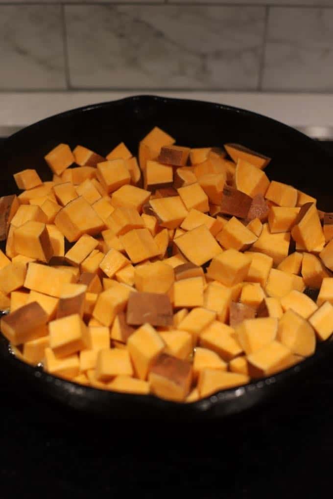 Cooking cubed sweet potatoes in a cast iron skillet.
