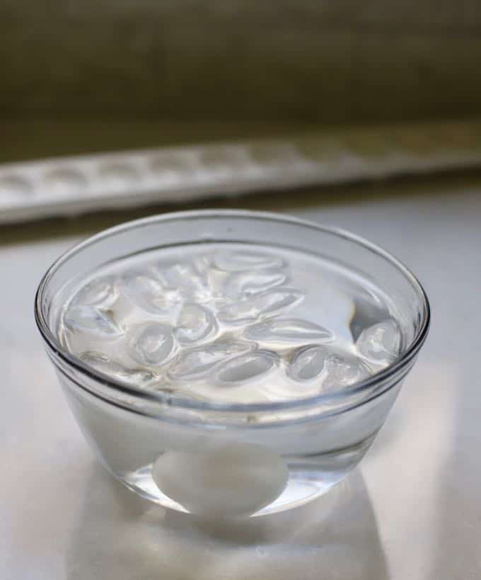 A bowl of water and ice cooling hard boiled eggs.