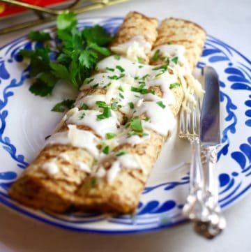 Two crepes on a blue and white plate with chicken and mushroom filling.