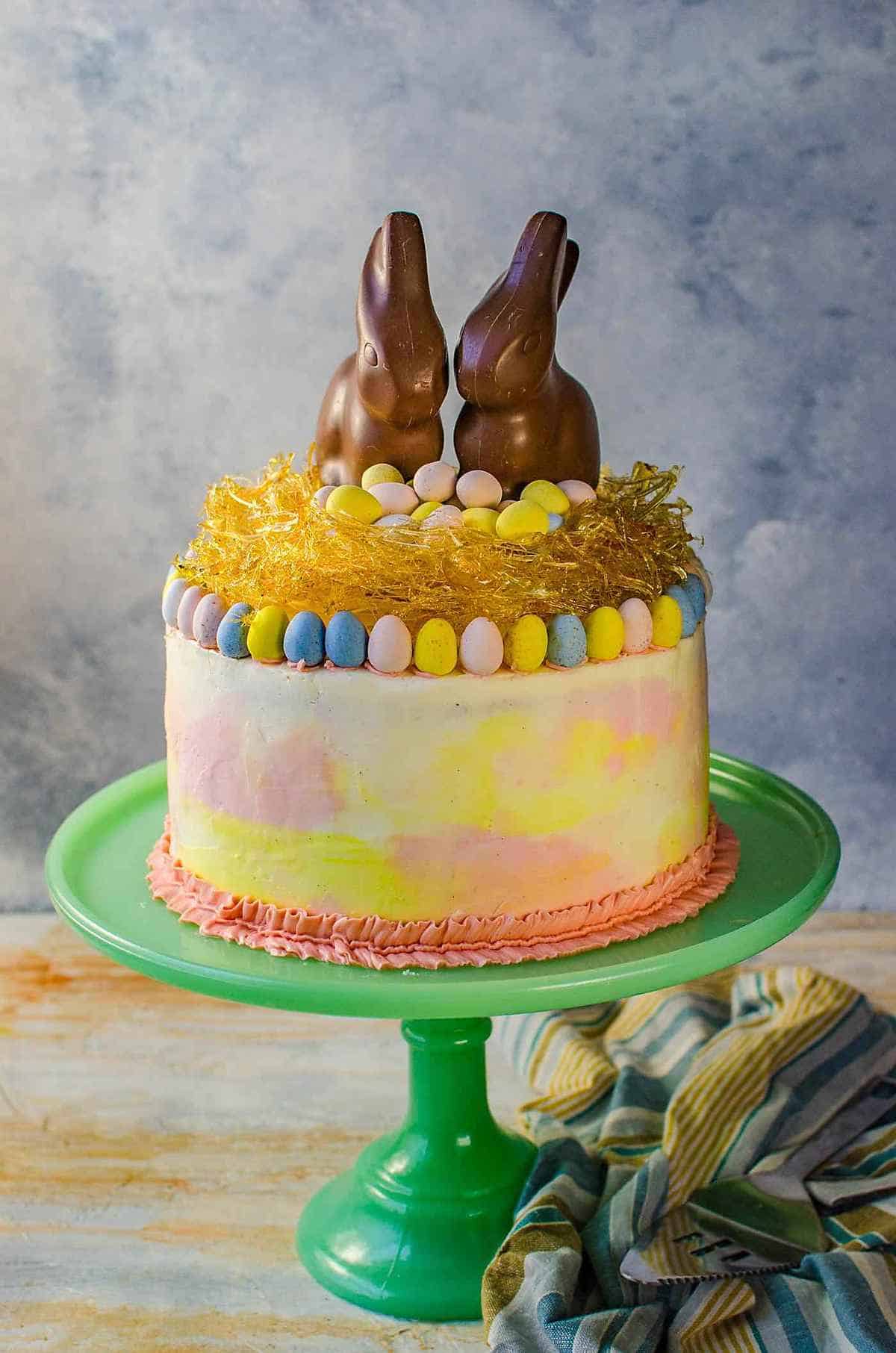 A cake on a cake stand topped with Chocolate Easter bunnies. 