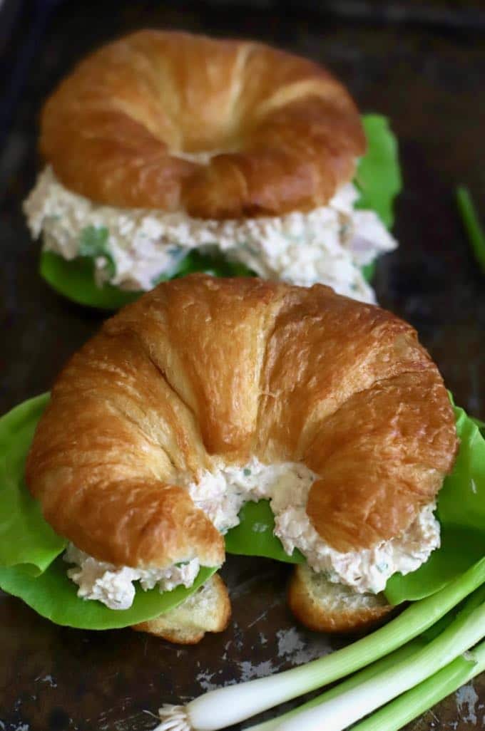 Two croissants with deviled ham filling garnished with scallions.