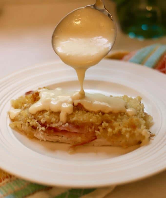 Spooning sauce over Easy Chicken Cordon Bleu Casserole.