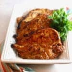 A white serving plate with several pieces of grilled teriyaki chicken.