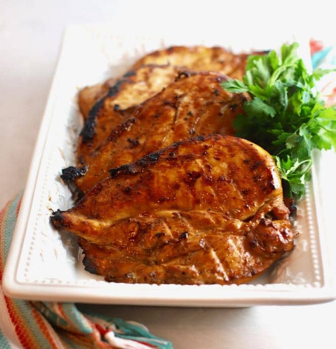 A white serving plate with several pieces of grilled teriyaki chicken.