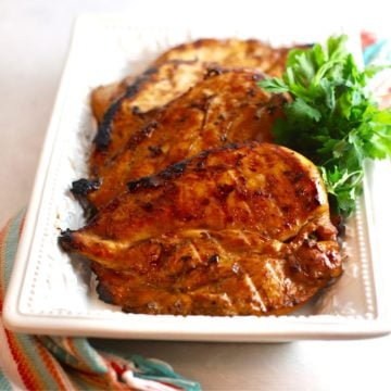 A white serving dish with several pieces of grilled teriyaki chicken.