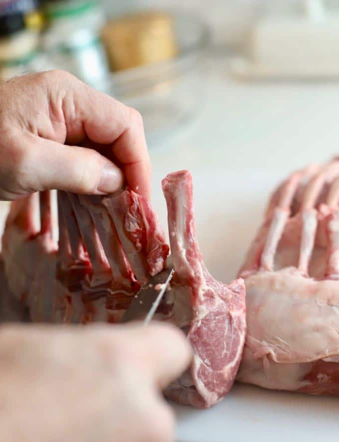 "Frenching", which is removing any remaining meat or fat, a rack of lamb before cooking.