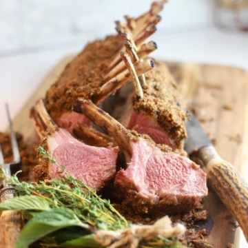 Two lamb chops cut from a rack of lamb on a cutting board.