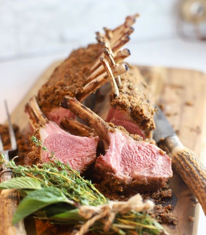 Two lamb chops cut from a rack of lamb on a cutting board.