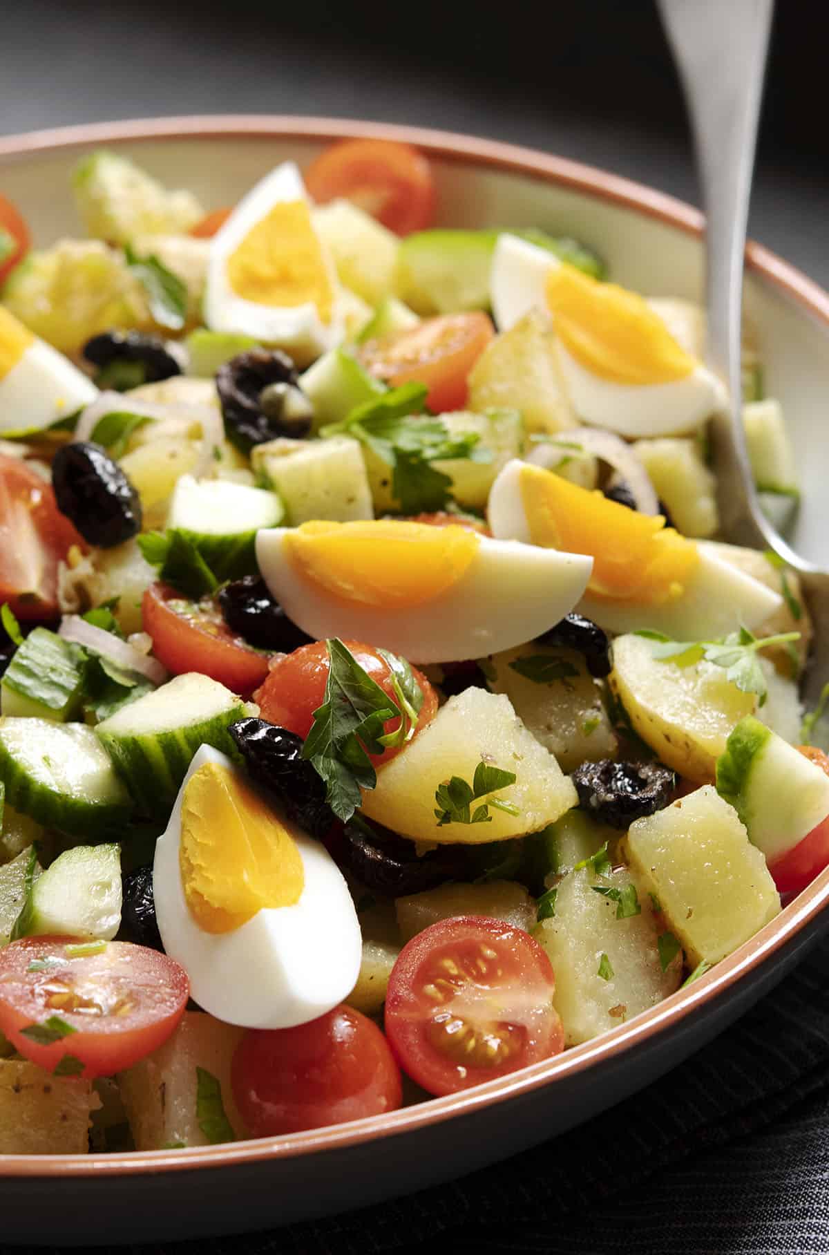 Greek potato salad in a bowl topped with hard-boiled eggs.