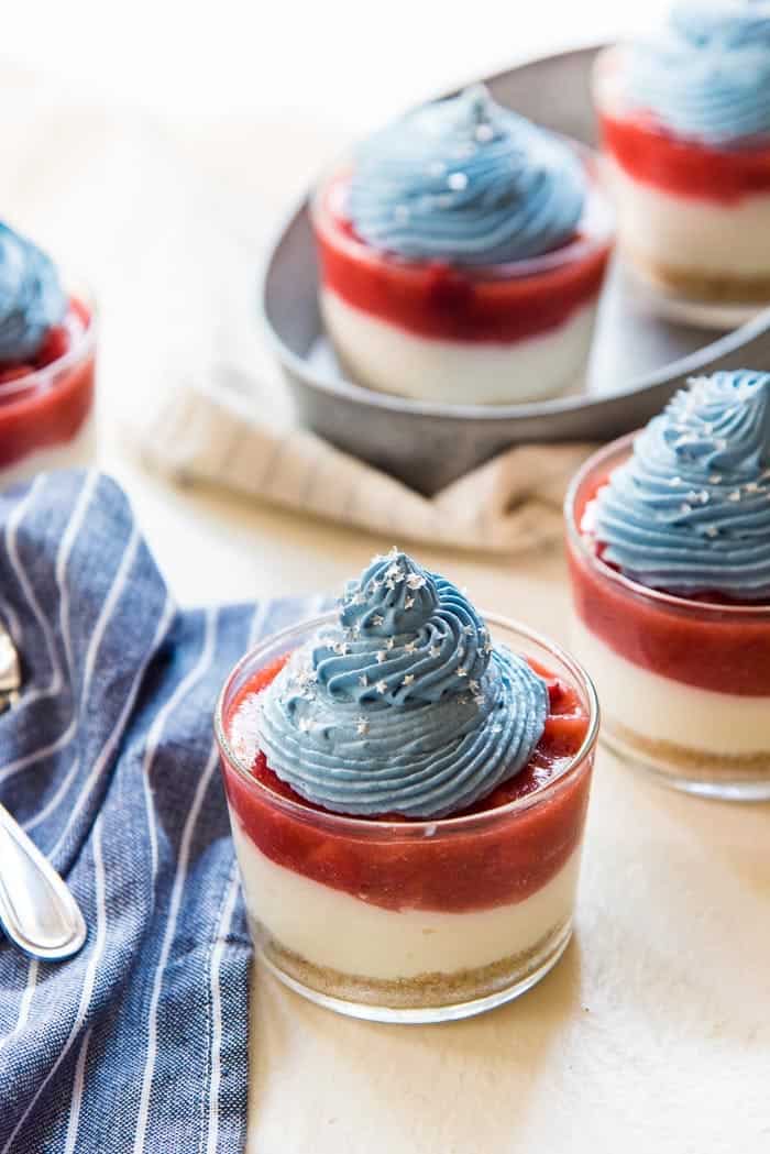 Three jars of coconut strawberry cheesecake in red, white, and blue layers. 