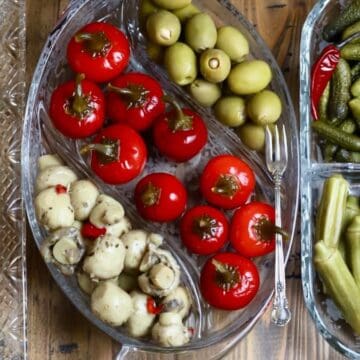 Glass relish trays with peppers, pickled okra, olives, boiled peanuts, and toasted bread slices.