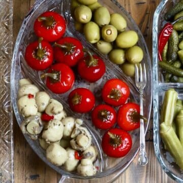 Glass relish trays with peppers, pickled okra, olives, boiled peanuts, and toasted bread slices.