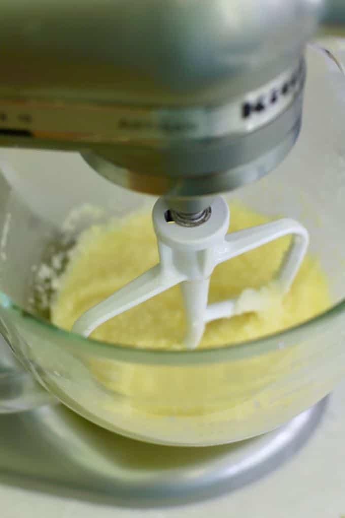 A stand mixer with a white beater mixing butter and sugar together.