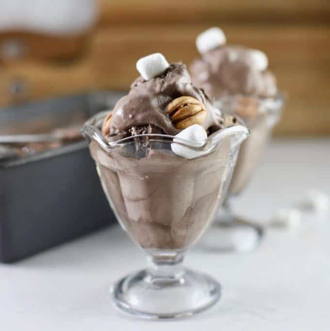 Rocky Road Ice Cream topped with marshmallows and pecans in a glass serving dish.