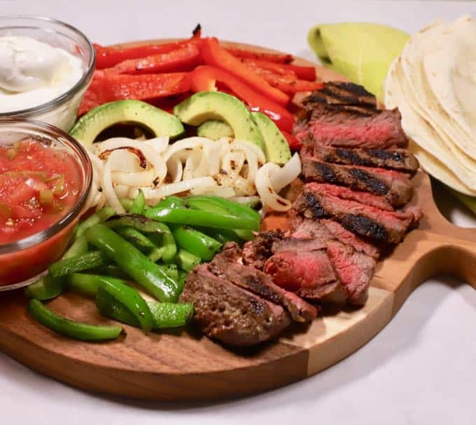 Grilled Steak Fajita ingredients on a wooden cutting board. 