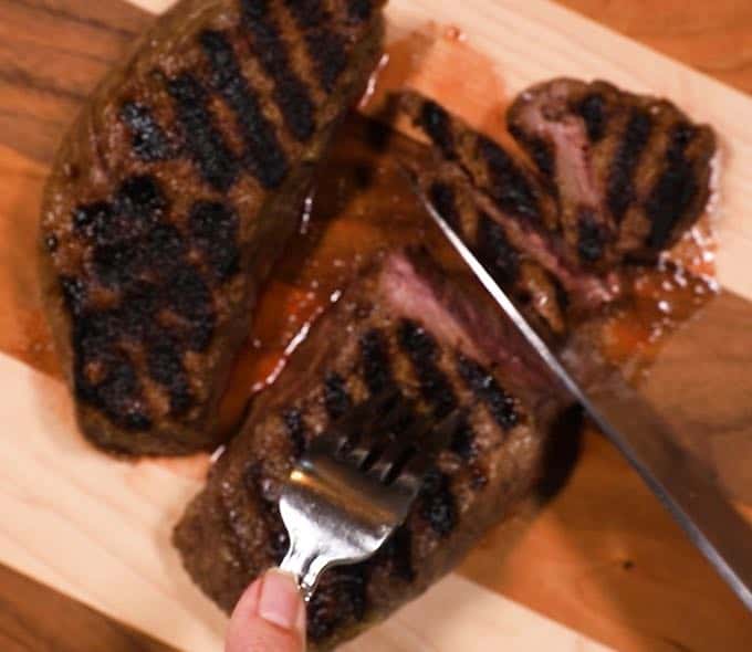 Slicing sirloin steak on a wooden cutting board.
