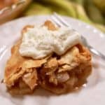 A piece of pear pie topped with whipped cream on a white plate.