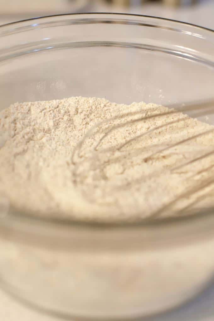 Flour, brown sugar, and baking powder in a clear glass bowl with a whisk.