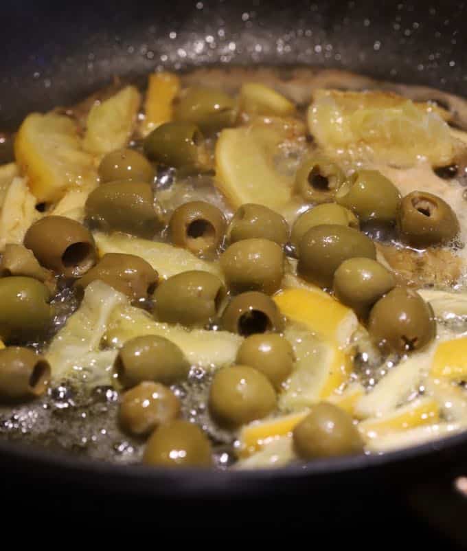 Cooking olives and lemon in a skillet. 