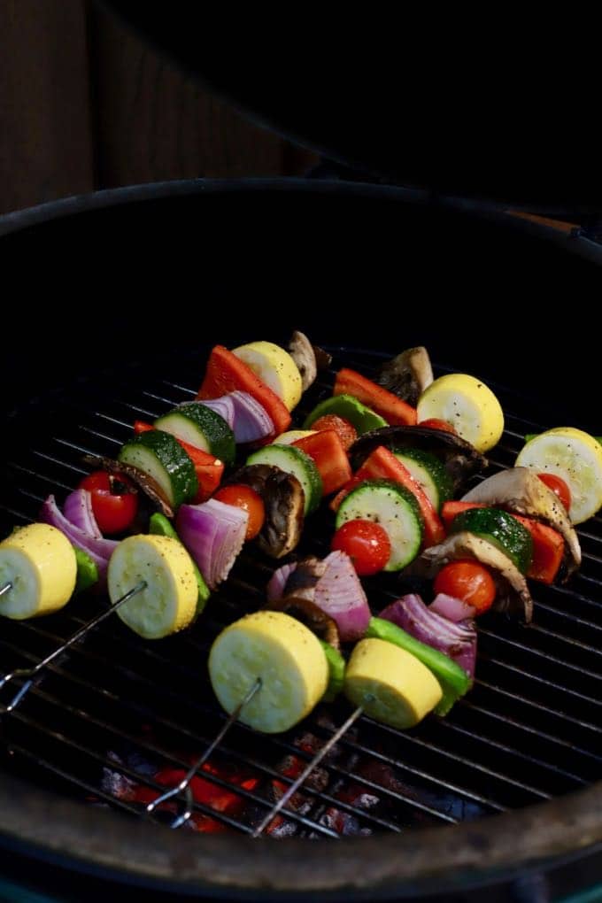 Four veggie skewers on a grill cooking. 