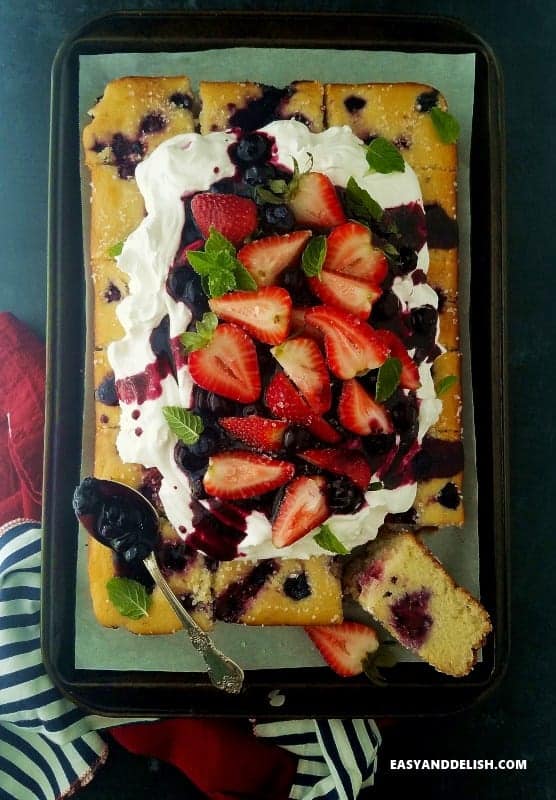 Easy and Delish Berry Cake topped with strawberries and blueberries.