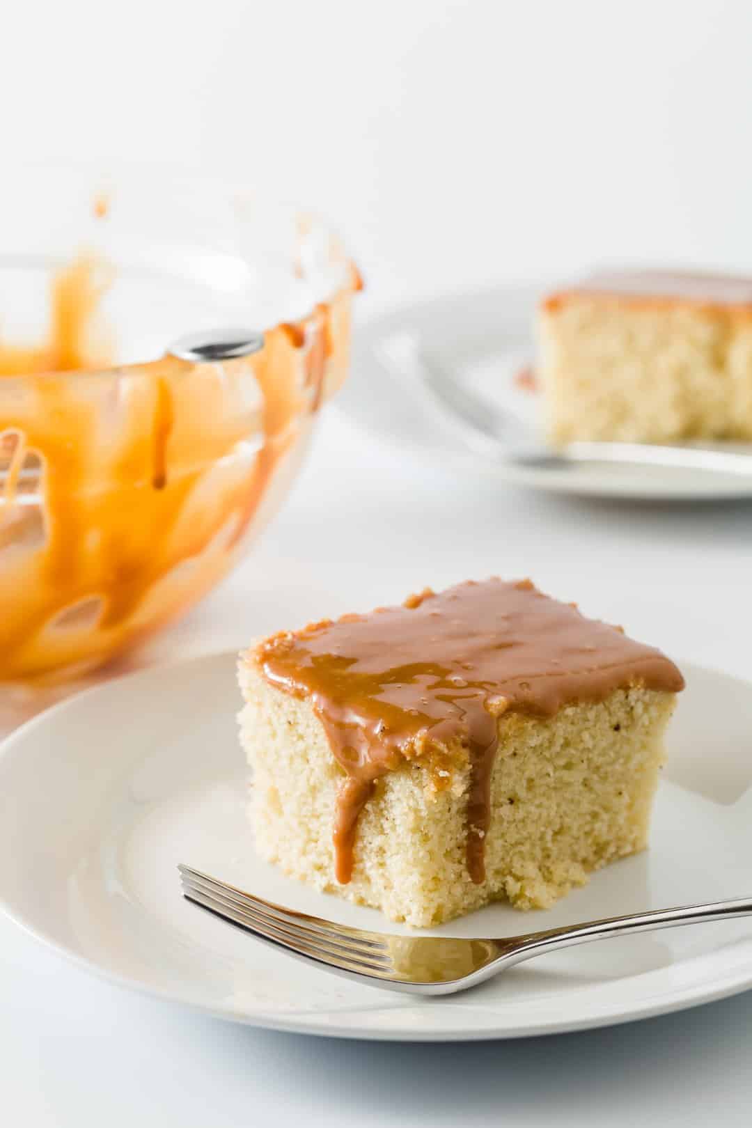 A slice of Dulce de Leche Cake on a white plate with a fork.