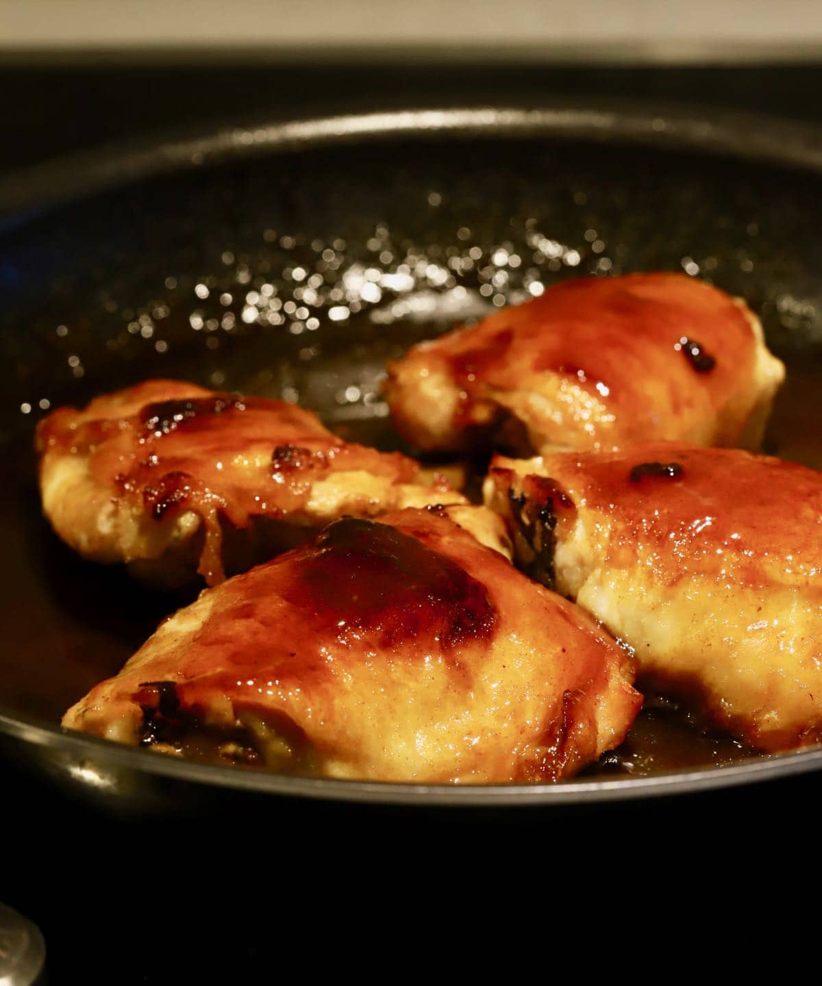 Four chicken thighs cooking in a skillet. 