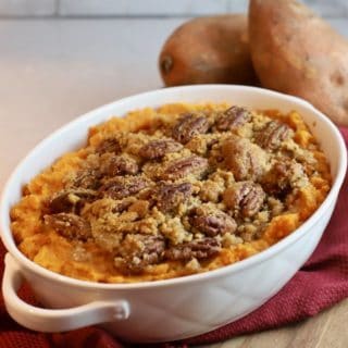 Southern Sweet Potato Casserole in a white baking dish with two raw sweet potatoes in the background.