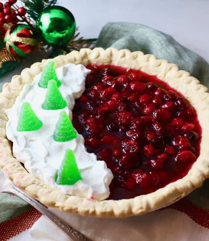 Christmas Cranberry Pie full of cranberry filling and topped with whipped cream and candy Christmas trees. 