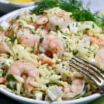 Shrimp Pasta Salad in a white bowl garnished with a sprig of dill.
