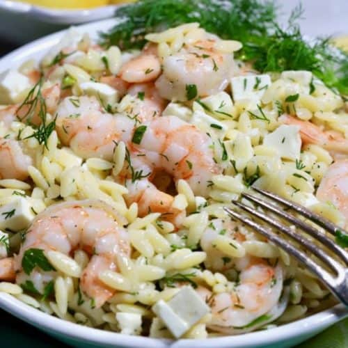 Shrimp Pasta Salad in a white bowl garnished with a sprig of dill.