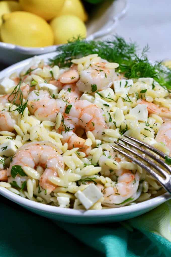 Shrimp Pasta Salad in a white bowl garnished with a sprig of dill.