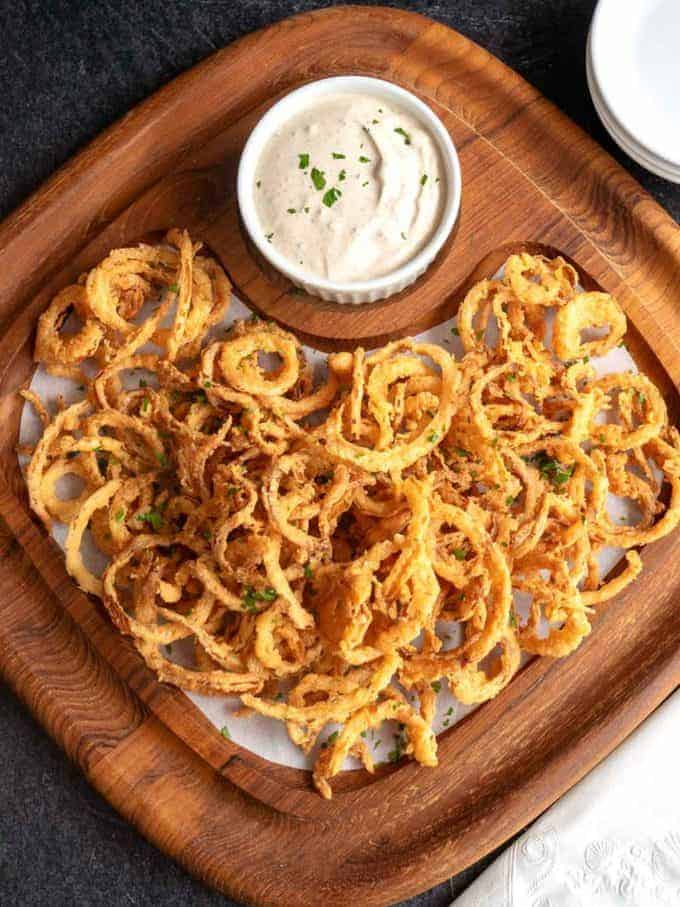 Cajun Onion Strings with a bowl of dipping sauce. 