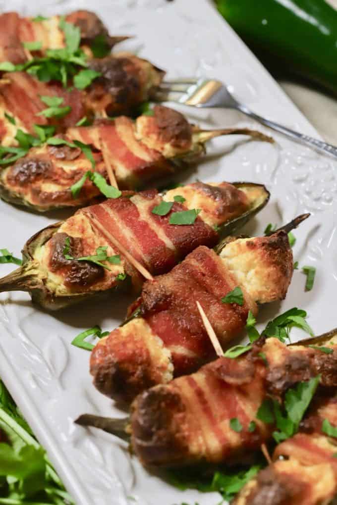 Game day appetizers, baked jalapeno poppers on a white serving platter. 