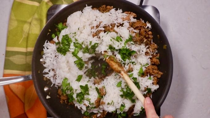 White rice, sausage, and parsley in a skillet. 