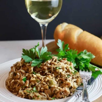 Dirty rice topped with parsley and a glass of wine.