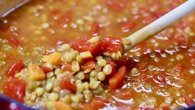 A wooden spoon with a spoonful of lentil soup.