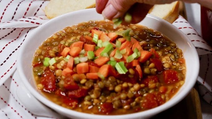 Topping lentil soup with chopped up carrots and celery.