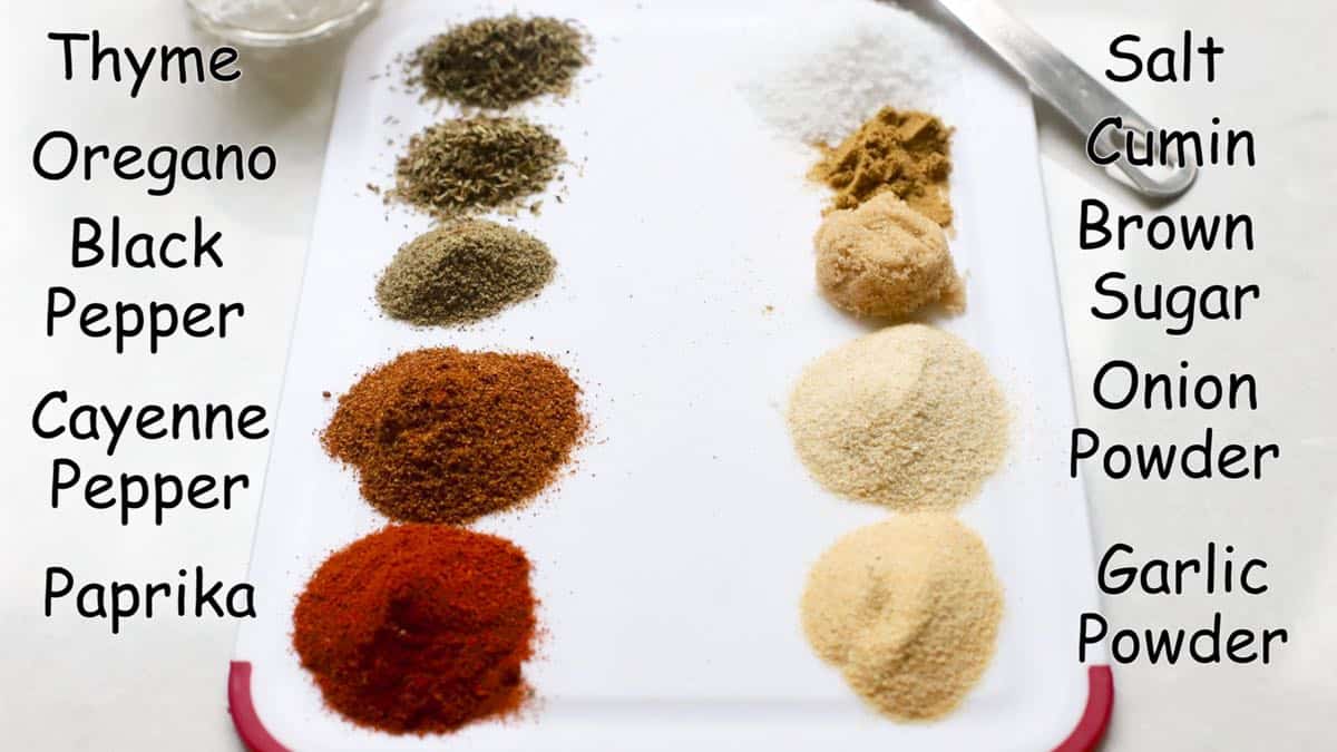 Spices including oregano and thyme as well as garlic and onion powder and paprika on a board to make blackened seasoning. 