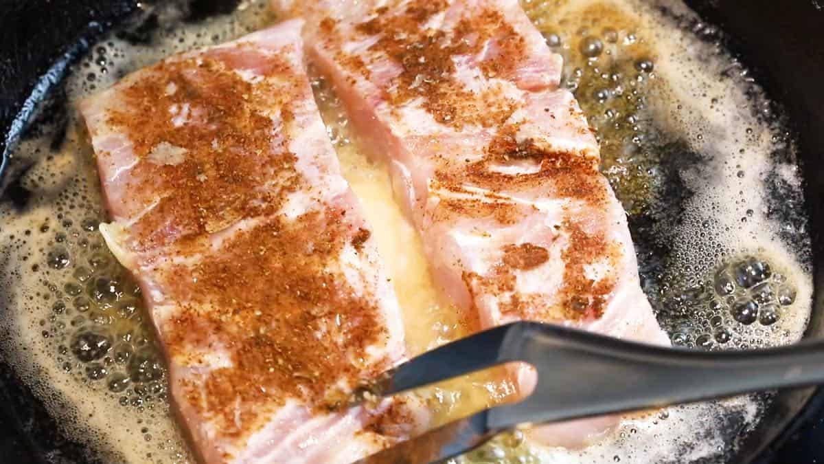 Cooking fish fillets in a cast iron skillet.