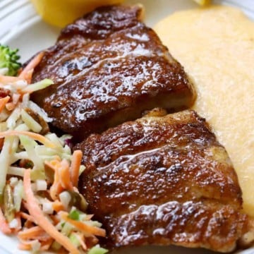 Blackened mahi-mahi with cheese grits and broccoli slaw on a white plate.