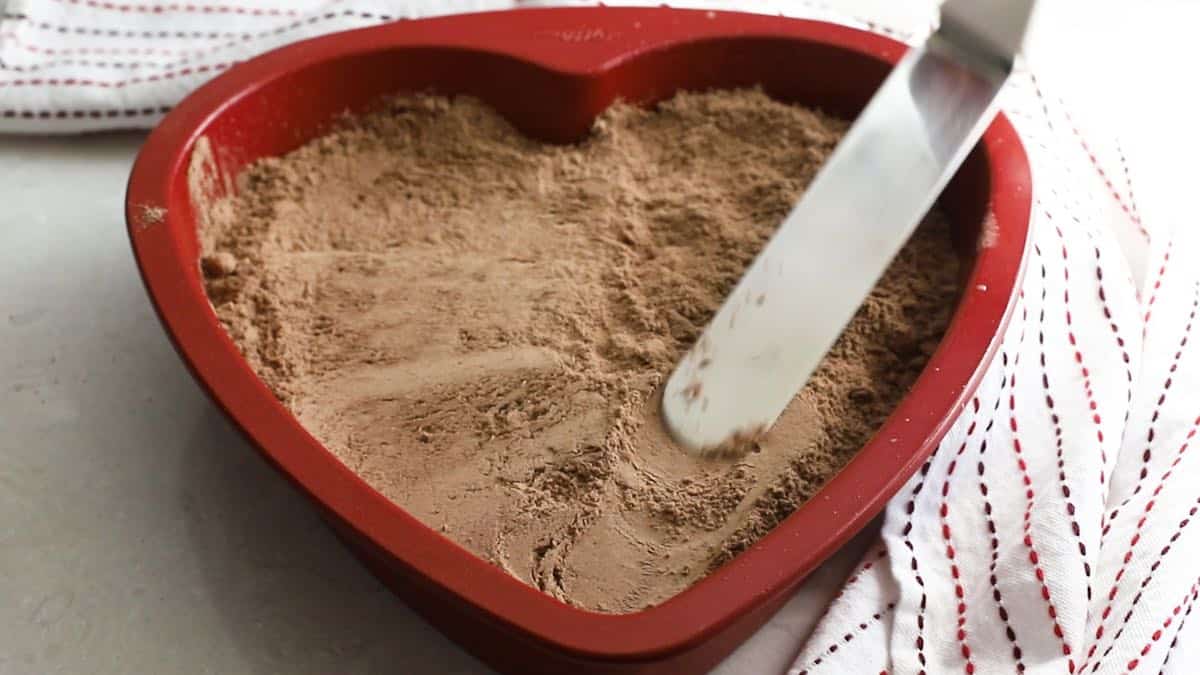 Dry chocolate cake mix in a red heart shaped baking pan. 