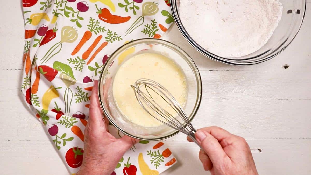 Mixing eggs and buttermilk in a clear glass bowl.