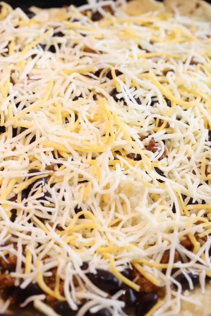 Shredded cheese covering nachos before baking. 