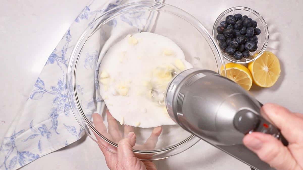 Butter and sugar in a clear glass mixing bowl. 