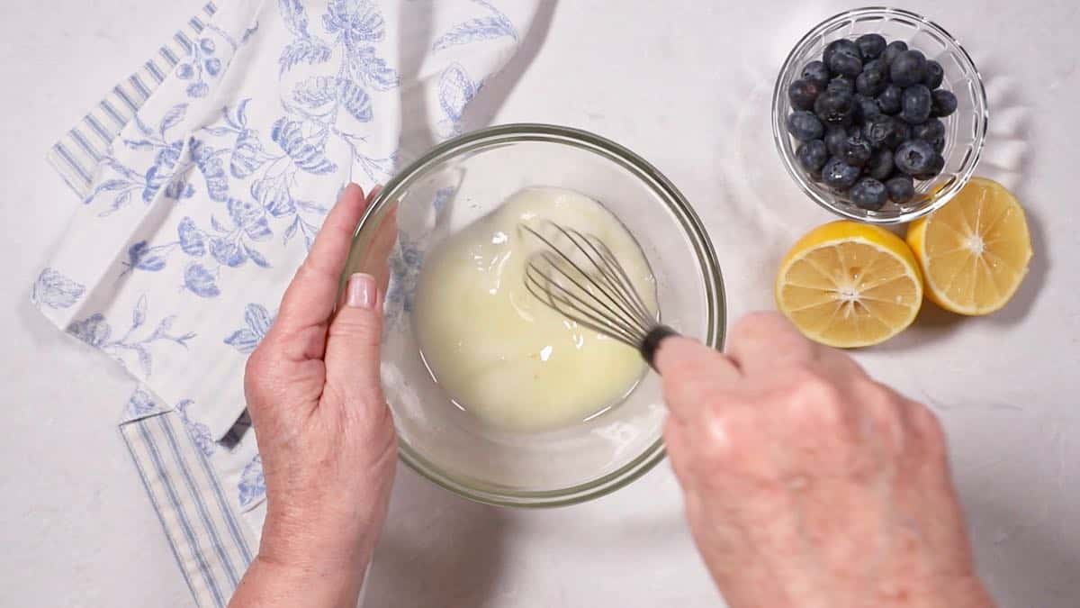 Whisking sugar and lemon juice in a bowl to make a glaze. 