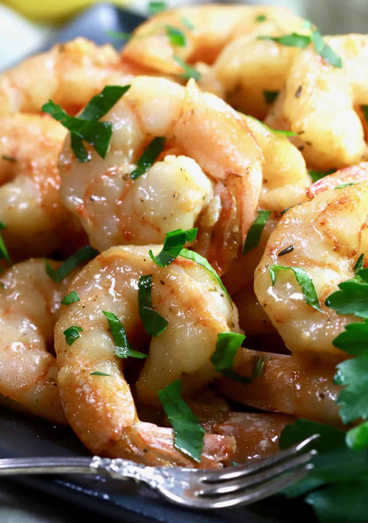 A close up shop of smoked shrimp piled high on a black plate. 